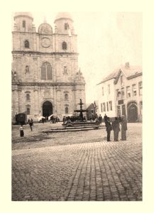 L'inévitable vue de la façade de l'abbatiale. Remarquez sur la droite les maisons qui referment assez fortement la place. Elles seront abattues entre 1933 et 1941. La porte cochère porte l'inscription Distillerie de liqueurs, E. Daniel. Les tentes installées à proximité de l'entrée de l'église abritent les vendeuses de béatilles qui, fidèlement, occupèrent l'endroit jusqu'à la fin des années 1960.