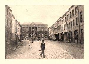 Cette vue du haut du Marché révèle des façades disparues. À droite, le (Grand) Café Universel, propriété de Constant Félix en 1900, a été remplacé en 1963 par une agence du Crédit Communal. Plus haut, cinq bâtiments détruits lors de l’incendie du 5 février 1933.
